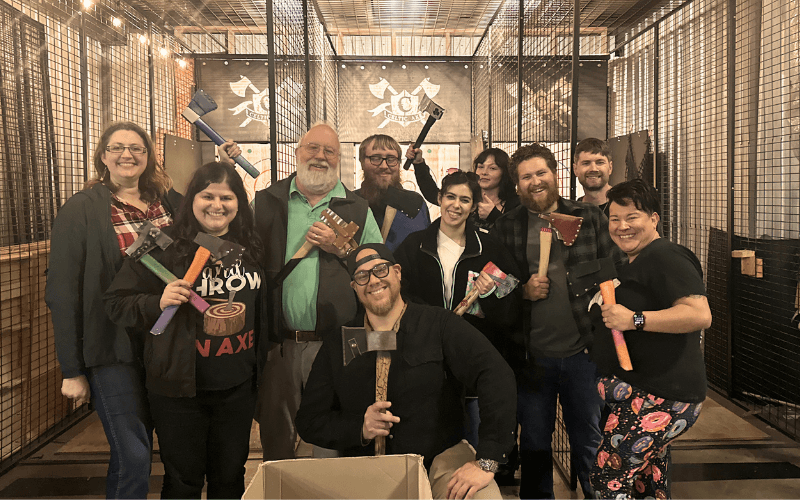 Group posing with axes between Celtic Axe throwing lanes