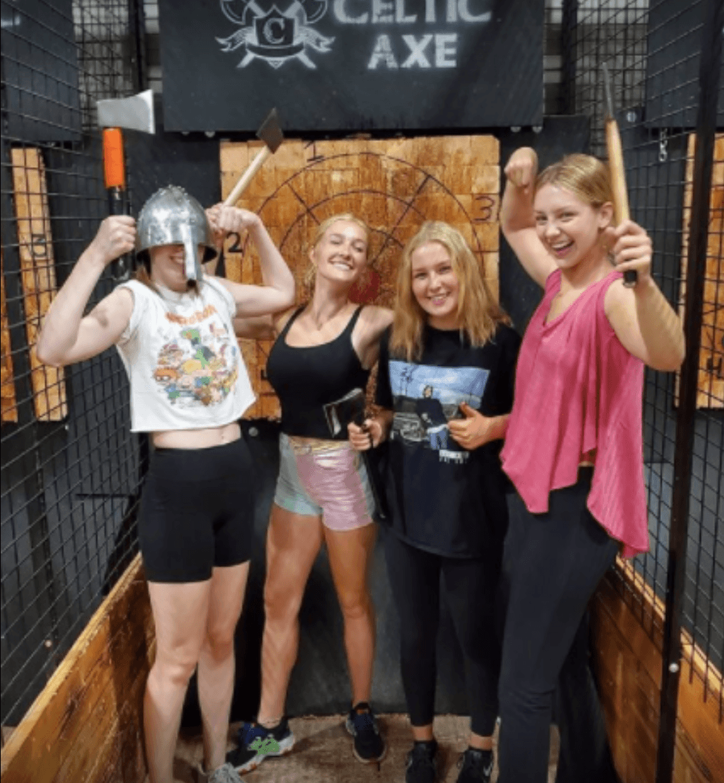Group of friends celebrating with axes in front of the Celtic Axe target board