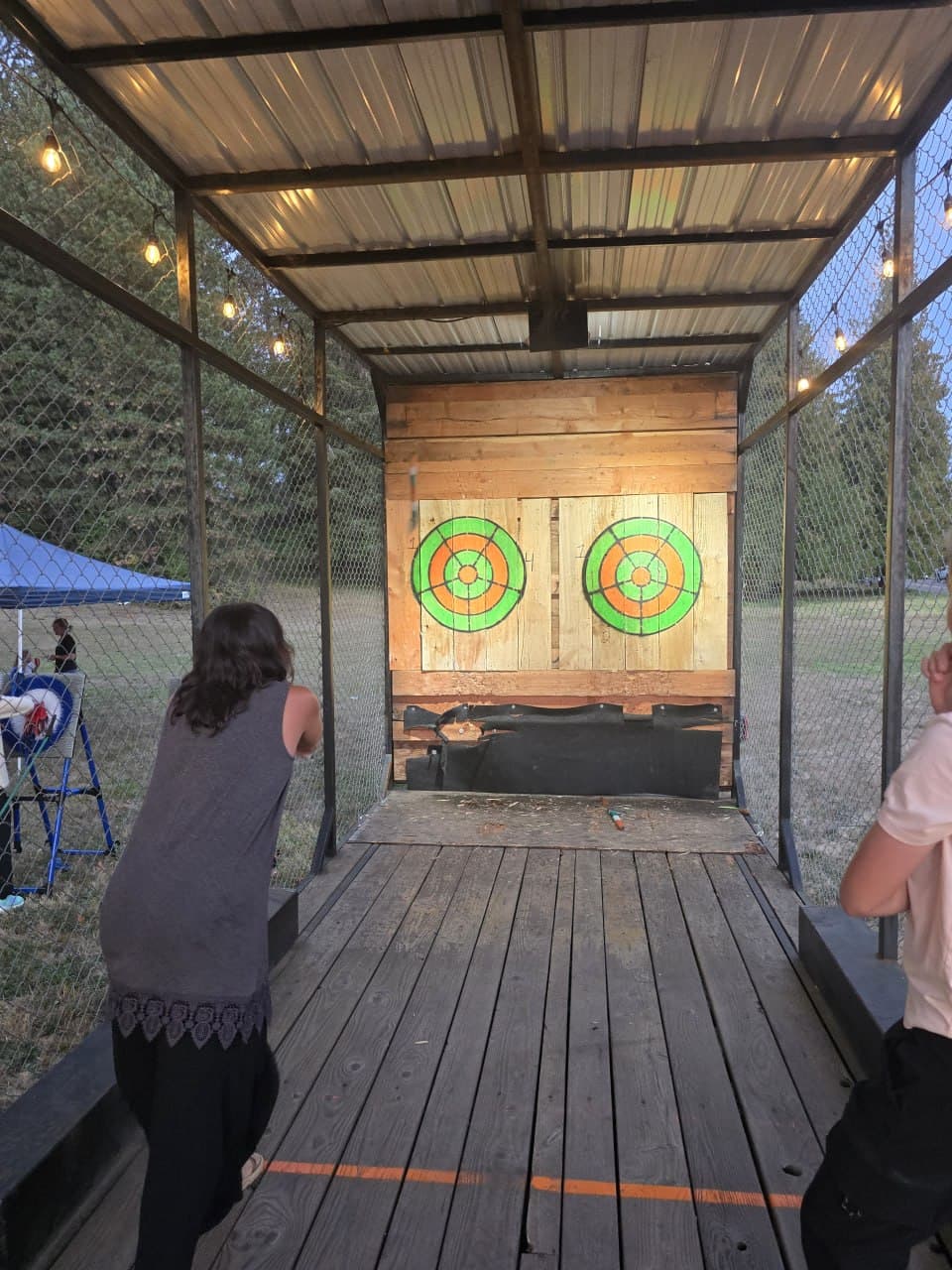 Guests throwing axes inside the Celtic Axe mobile trailer